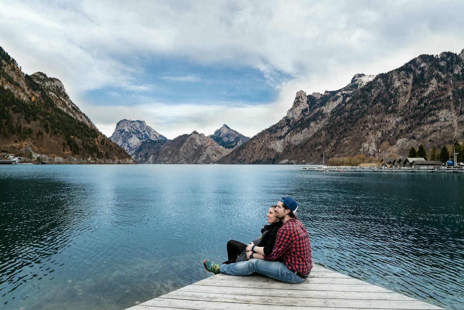 man and woman sitting on brown wooden dock