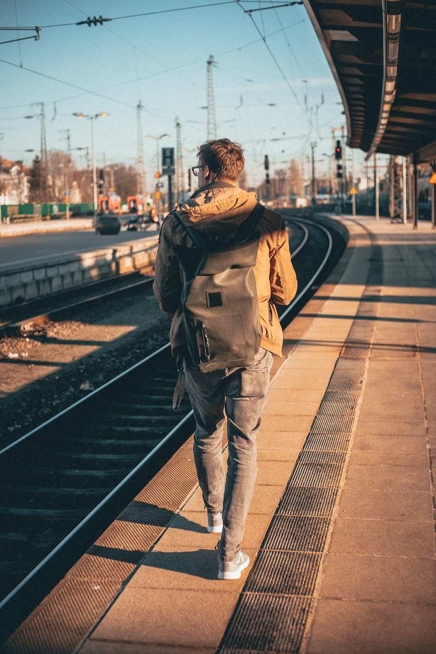 man in brown top beside railroad