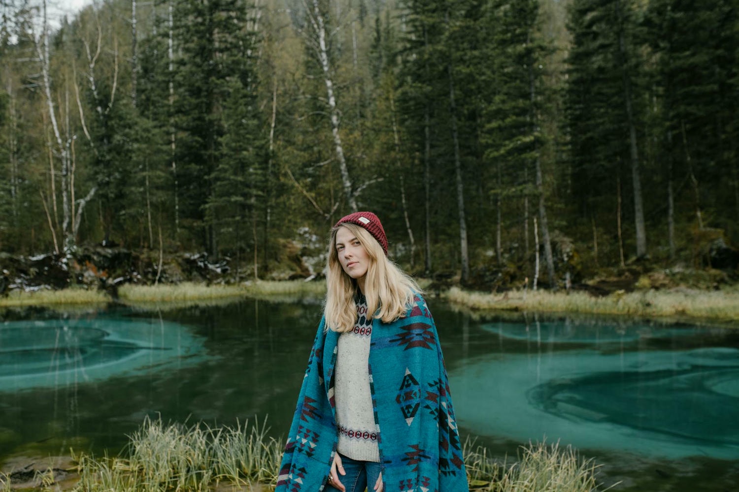 young woman standing on lakeside in forest