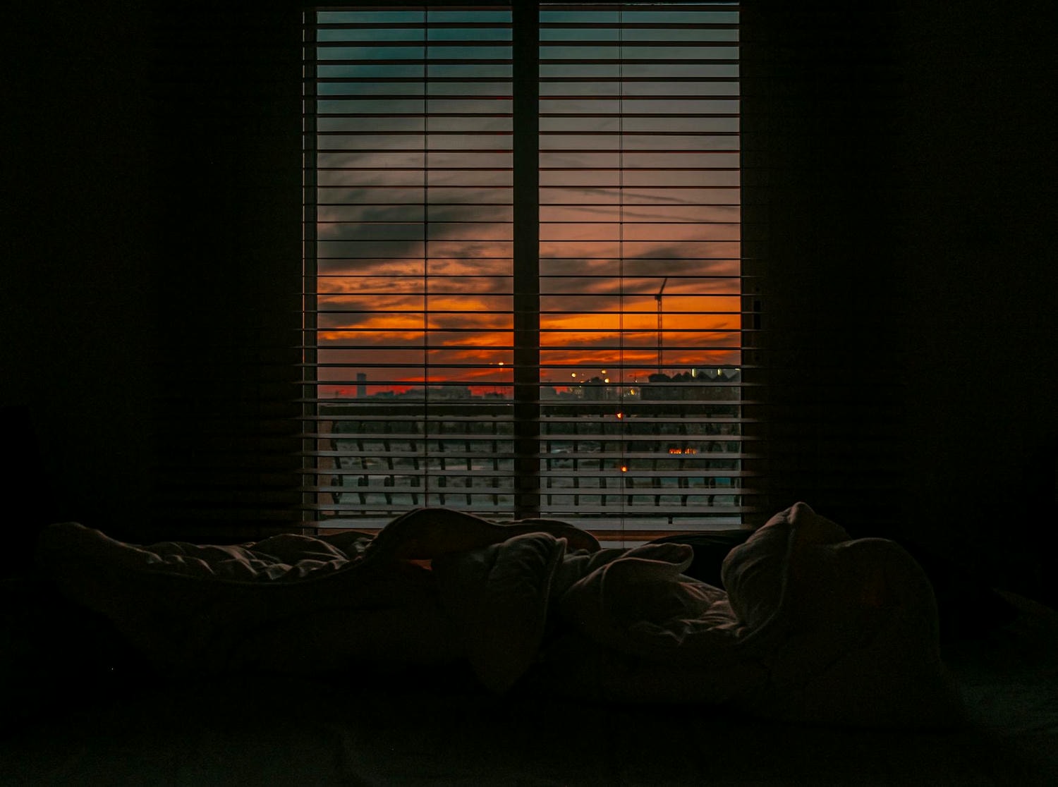 crumpled blanket in dark room at sunset