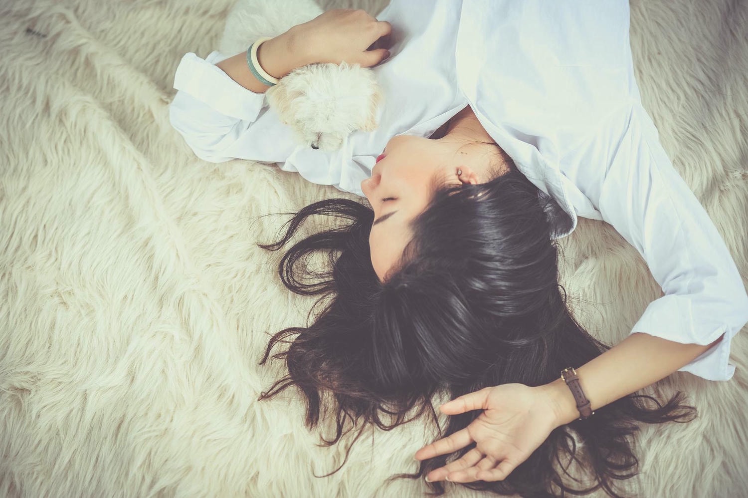 woman lying on beige faux fur mat