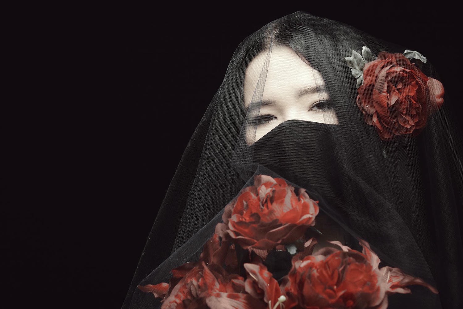 woman in black hijab with red rose petals