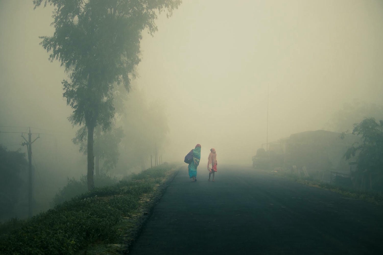 anonymous ethnic females strolling along road on misty day