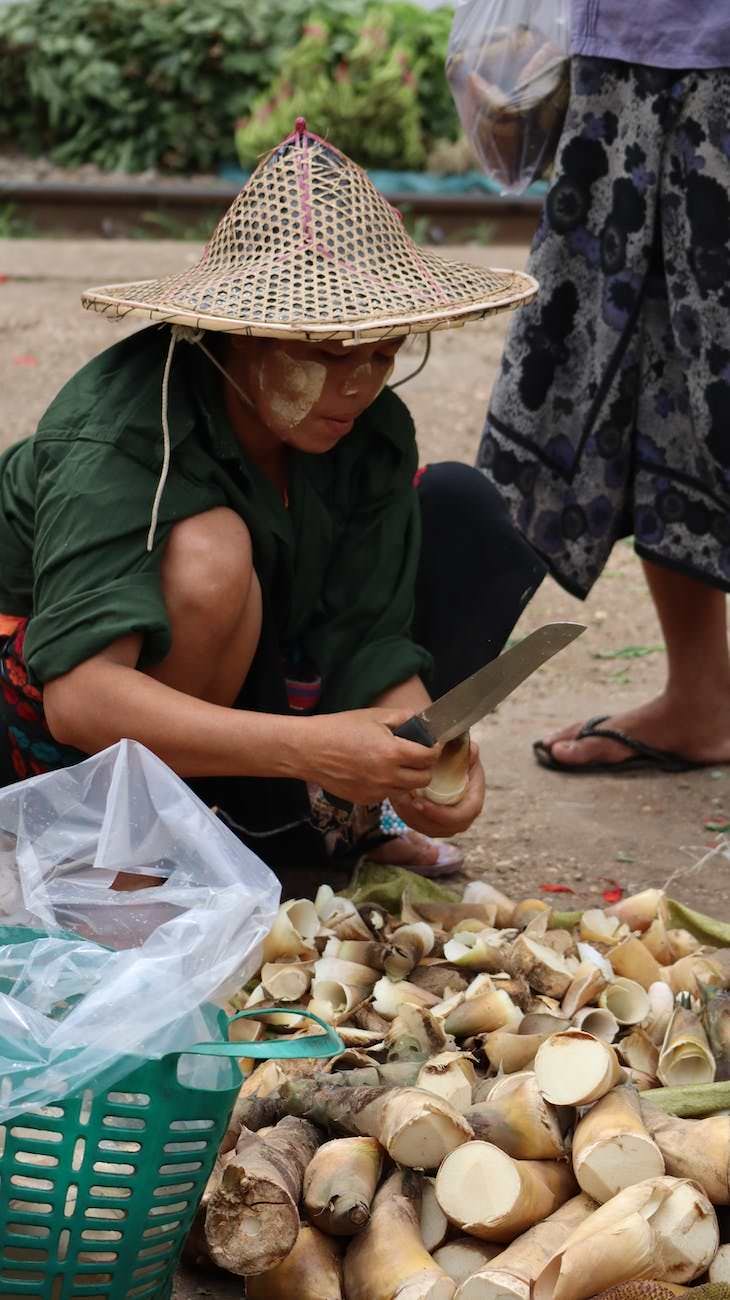 woman in green shirt and conical hat holding a knife